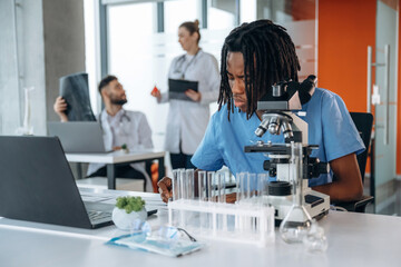 Professional microscope is on the table. Doctors are in the clinic