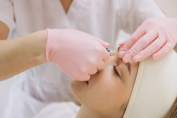 Doctor performing botulinum toxin injection for rejuvenating facial treatment in beauty parlor