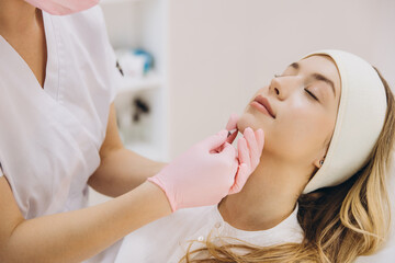 Cosmetologist performing botox injection treatment on patient's face for anti aging and wrinkle smoothing in beauty clinic