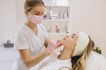 Cosmetic professional injecting botox into patient's lips, performing precision aesthetic treatment...