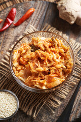 Fermented kim chi in a glass bowl with chilli peppers, sesame seeds and ginger