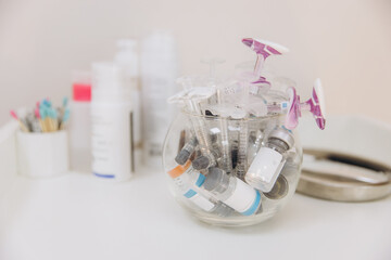 Syringes and medicine vials for botox injections inside a glass bowl, on a table in a cosmetology...