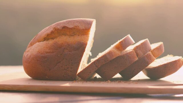 Outdoors Morning Sunlight on Freshly Baked Homemade White Bread Loaf with Slices on Wooden Chopping Board with Fields Background. Home Baking Footage with Simple Healthy Ingredients 4K.