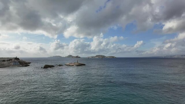 A timelapse of If Island and its Castle in fornt of Marseille city under a changing sky with some fluffy clouds. 4K