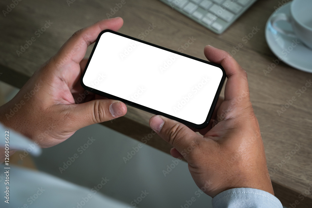 Poster a smart person is using a laptop and smartphone at a modern office desk, holding a phone in one hand