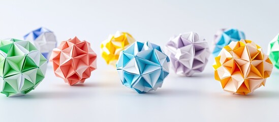 Colorful modular origami balls arranged in a row featuring vibrant green, pink, orange, purple, and yellow against a bright white background.