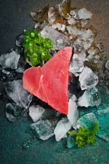 Close up of raw tuna steak on crushed ice. On dark background. Top view.