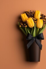 Bright lemon-yellow tulips elegantly arranged with slate-blue ribbon on a soft peach backdrop, creating a charming floral display