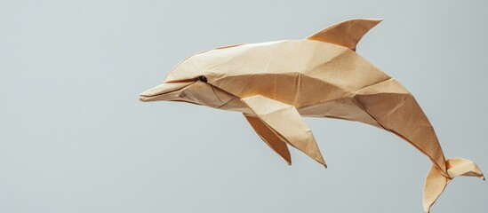 Kraft paper origami dolphin in a light gray background showcasing intricate folds and a three-dimensional appearance capturing a playful pose. © Rasim