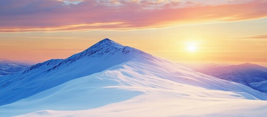 Serene sunrise over snow-covered mountain peak with soft pastel colors in the sky and bright sun illuminating the landscape below