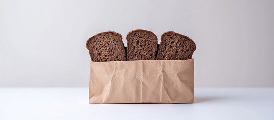 Freshly sliced dark brown bread in a kraft paper bag centered on a white background, showcasing textures and details of the bread.