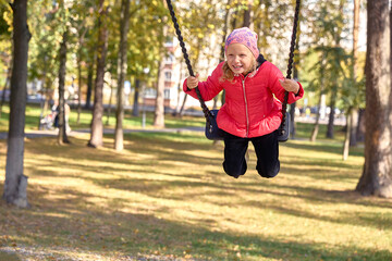 A little girl is swinging on a swing.
