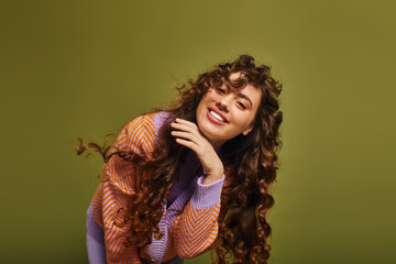 Stylish young woman with curly hair posing against a vibrant green backdrop