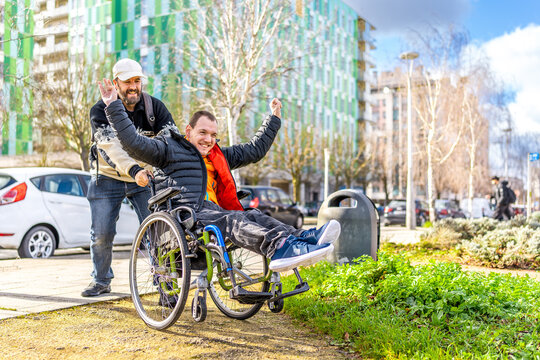Caregiver pushing happy disabled man in wheelchair in the city