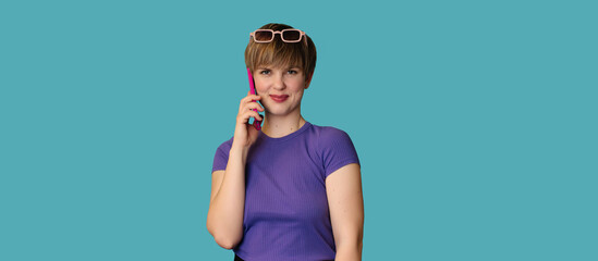 Caucasian young woman is talking sweetly on a mobile phone on a blue background. Panoramic banner. A place for your text. Technology concept