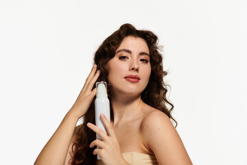 Obraz premium Stylish young woman applying beauty product with confidence in a bright studio setting