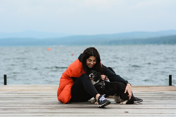 Woman Hugging her Adopted Black Dog on a Lake Background