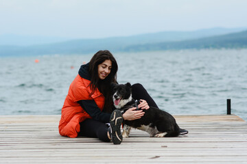 Woman Hugging her Adopted Black Dog on a Lake Background