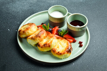 Breakfast. Cheese pancakes with sour cream and fruit on a plate. On a black stone background.