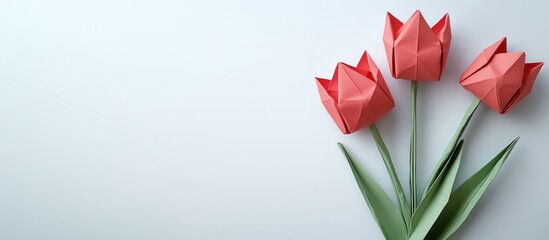 Three vibrant red origami tulips with green leaves arranged on a soft pastel background, positioned in the bottom right corner of the image.
