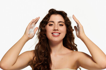 Radiant young woman showcasing her skincare routine with confidence in a clean studio space