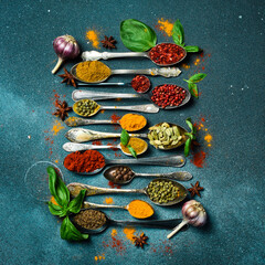 Set of spices and herbs in vintage spoons. Colorful various spices for cooking. On a black slate background.