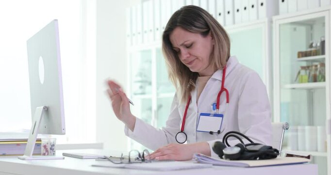 Female medic analyzes documents on computer ignoring excess data in clinic. Woman doctor fills patient records reading digital files in office