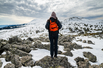 Fototapeta premium Beautiful young woman standing in the high winter mountain with stunning view 