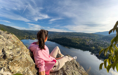 Naklejka premium Traveler woman sitting on a rocks high above a blue lake 