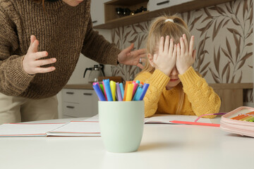 Exhausted elementary school girl is tired of doing homework, stressed with difficult task, sitting...