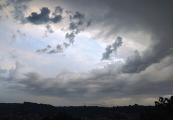 Dramatic cloud formations over a hillside town in the late afternoon sunlight highlighting the landscape's beauty