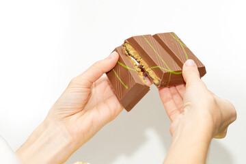 Obraz premium Trend Dubai chocolate with pistachio paste and kataifi in a woman’s hand on a white background 