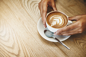 Hands, latte art and space with person in coffee shop for hospitality, relax or service. Artistic, beverage and wooden table with customer in cafe or restaurant for morning caffeine drink from above