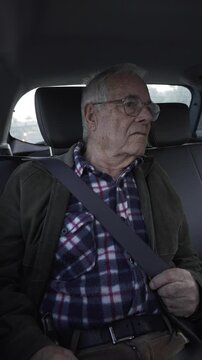 vertical video of passenger in the back seat, elderly person over 80 years old, looking out of the window at the traffic and driving.