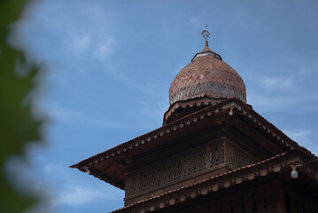 View of an old wooden mosque in Indonesia with walls decorated with beautiful ornamental carvings