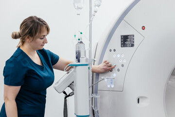 A medical nurse, doctor push buttons of a modern MRI scanner while attending to a patient in a...