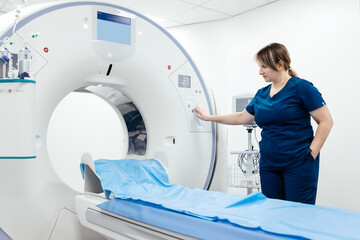 A medical nurse, doctor operates a modern MRI scanner while attending to a patient in a medical...