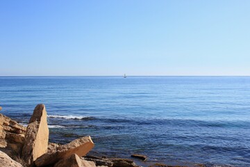 a small white sail boat went out to sea on a clear sunny day
