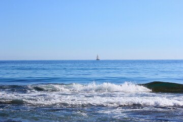 a small white sail boat went out to sea on a clear sunny day