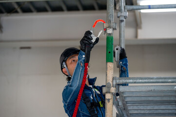 足場に安全帯をかける日本人男性作業員