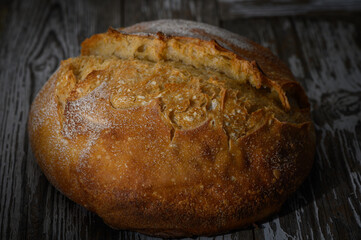 Warm, crusty loaf of artisan bread resting on rustic wooden table after baking
