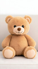 Obraz premium Cute plush teddy bear sitting on a couch indoors. Soft toy for kids, gift