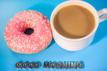 A white coffee cup and a pink frosted donut with white sugar pieces sit next to metallic text 