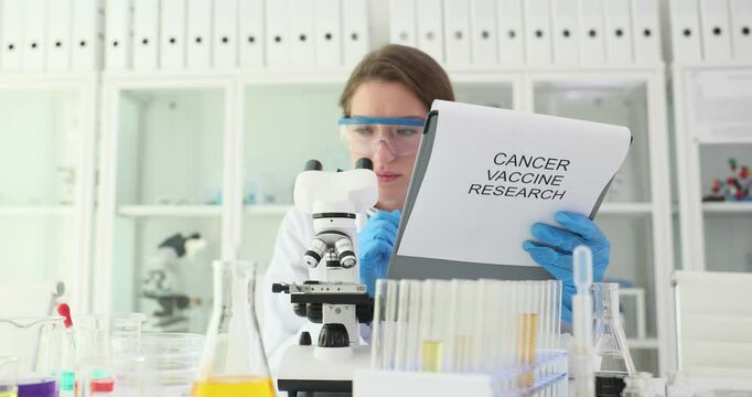 Medical scientist investigates cancer vaccine analyzing research data through microscope holding clipboard. Woman pharmacist works in sterile laboratory