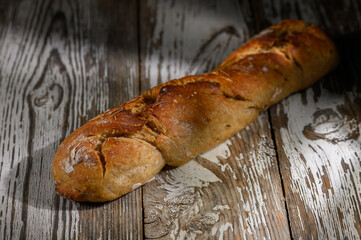 Rustic loaf of artisan bread resting on a weathered wooden table in soft lighting