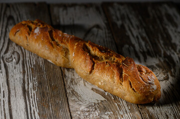 Freshly baked rustic bread loaf resting on an aged wooden table illuminated by soft, warm light