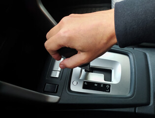 Closeup of a hand shifting an automatic cars gear stick.  The image showcases the interior detail, perfect for automotive, transportation, or drivingrelated projects. Clean and modern aesthetic.