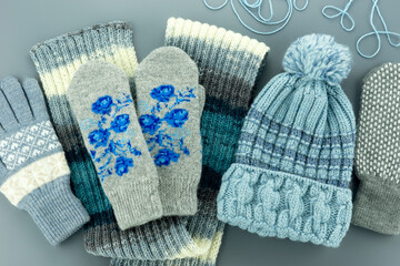 Hat, mittens, scarf, gloves in blue and gray colors. Warm knitted clothes for autumn and winter.