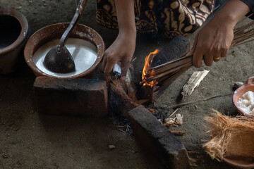 A village woman in Indonesia prepares firewood for cooking. The activity of cooking traditional cakes on a clay stove