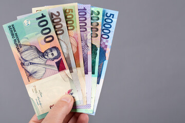 Old Indonesian money in the hand on a gray background